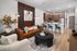 Chic open-plan living room with a cozy leather sofa, modern art accents, and a sleek kitchen island with blue stools.