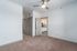 Bright and spacious bedroom with plush carpeting, modern ceiling fan, and an inviting view into the sleek, open kitchen.