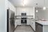 Modern kitchen with sleek stainless steel appliances, elegant white cabinetry, and a chic granite countertop, illuminated by stylish pendant lighting.