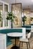 Modern dining area featuring elegant round tables, chic green seating, and stylish globe pendant lighting.