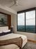 Elegant bedroom with panoramic window views and cozy decor, featuring a plush bed and modern ceiling fan.