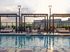 Luxury rooftop pool surrounded by stylish lounge chairs and chic pergolas, offering stunning cityscape views and a perfect sunset vibe.