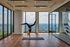 Bright and airy yoga studio with floor-to-ceiling windows offering a breathtaking city view, showcasing a serene exercise atmosphere.
