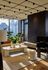 Chic, modern living room with floor-to-ceiling windows offering stunning city views, featuring a cozy fireplace, stylish furniture, and lush greenery for a relaxing atmosphere.