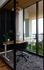 Contemporary office space with glass walls, wooden desk, and lush balcony view.
