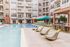 Luxurious apartment complex courtyard featuring a glistening pool, stylish lounge chairs, and vibrant umbrellas for ultimate relaxation.