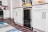 Sleek modern kitchen featuring elegant white cabinetry, stylish wine cooler, and chic granite countertops, perfect for culinary enthusiasts.