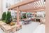 Chic apartment courtyard featuring a stylish pergola, modern outdoor dining area, lush greenery, and built-in barbecue station.