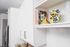 Sleek modern kitchen with white cabinetry, colorful dishware, and stylish cookbooks on display for a vibrant touch.