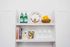 Chic kitchen shelf boasting elegant decor, featuring designer books, vibrant bowls, and a stylish lemon display.