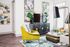 Modern living room with vibrant decor, featuring a lime green chair, stylish abstract wall art, and a wooden media console with a sleek TV.