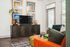 Chic living room with colorful abstract wall art, modern TV stand, vibrant decor, and ample natural light through tall windows.