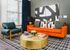 Chic apartment living room with vibrant orange sofa, bold abstract art, and a luxurious gold coffee table on a patterned rug.