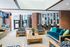 Vibrant and inviting communal lounge area with modern wooden furniture, bold patterned upholstery, and a cozy fireplace, ideal for relaxation and socializing.