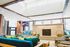 Bright and airy living room with large skylight, modern green and teal seating, and cozy fireplace accents.