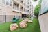Inviting pet-friendly outdoor space with agility equipment and vibrant green artificial turf next to a modern apartment building.