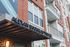 Elegant modern entrance of Alexan Buckhead Village showcasing contemporary architecture with sleek balconies and a welcoming awning.