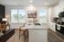 Modern open kitchen featuring a sleek granite countertop island with seating, adjacent to a cozy living space with natural light from large windows.