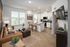 Bright and inviting open-concept living space featuring a modern kitchen with sleek white cabinets, cozy seating area with a leather sofa, and large windows allowing natural light to fill the room.