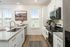 Bright and modern kitchen with sleek granite countertops, stainless steel appliances, and elegant cabinetry, enhanced by large windows offering natural light.