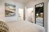 Chic bedroom with contemporary wall art, sleek mirror, and stylish bedding, leading to a modern walk-in closet.