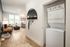 Modern apartment hallway featuring a stacked washer and dryer, elegant wooden floors, and a cozy living area with abundant natural light.