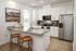 Modern kitchen with sleek granite countertops, stylish bar stools, stainless steel appliances, and plenty of natural light.