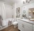 Bright and modern bathroom featuring granite countertops, sleek white cabinetry, and a stylish bathtub with a curved shower rod.