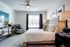 Inviting bedroom with plush bed, chic patterned armchair, and stylish decor in a bright, sunlit space.