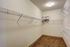 Spacious walk-in closet with ample shelving, ideal for organized storage, featuring modern lighting and plush carpet.