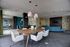 Modern communal space in an apartment building featuring stylish teal and white furniture, elegant wooden dining table, and contemporary lighting.
