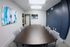 Contemporary conference room with a sleek dark wood table, modern chairs, and eye-catching abstract art. Spacious and well-lit, ideal for productive meetings.