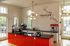 Modern caf&eacute; interior with sleek design, featuring a stylish espresso bar with vibrant orange accents and a 'Trapeze' wall mural, offering a bold and inviting atmosphere.