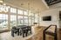 Luxurious living area with panoramic windows, modern chandeliers, and a stylish game setup in a sunny apartment.