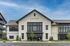 Charming modern building with elegant architecture and inviting entrance, boasting large windows and manicured landscaping under a bright blue sky.