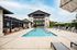Luxurious apartment complex featuring a stylish pool area with modern lounge chairs and shaded seating beside a chic multi-story building.