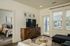 Inviting living area with modern decor, featuring a stylish television stand, chic seating, and a glimpse into a cozy bedroom with elegant furnishings.