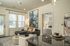 Elegant modern living room with a cozy gray sectional, abstract art, adjacent bedroom view, and stylish kitchen island.