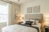 Elegant bedroom with modern decor, featuring a cozy bed with stylish cushions, artistic wall pieces, and warm lighting, creating a serene ambiance.