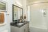 Elegant bathroom with sleek black granite countertop, large mirror, and modern white bathtub, perfect for a stylish home.
