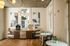 Elegant corner of a modern apartment featuring chic wall art, warm wood flooring, and stylish light fixtures with a cozy dining area and beverage station.