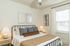 Inviting bedroom with a cozy double bed, stylish pillows, and elegant artwork, bathed in natural light.