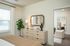 Inviting bedroom with stylish decor, featuring a chic dresser, elegant mirror, lush indoor plant, and cozy seating area, perfect for relaxation.