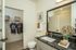 Modern bathroom with sleek design featuring a granite countertop, stylish mirror, and walk-in closet with organized shelving and clothing.