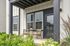 Charming apartment patio with stylish wooden chairs, a sleek table, and vibrant greenery, perfect for relaxing outdoors.