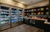 Modern apartment convenience store with fully stocked refrigerators and shelves featuring a diverse selection of drinks, snacks, and gourmet goodies.
