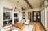 Elegant living space featuring modern design with plush chairs, a wooden coffee table, and stylish lighting. Abundant natural light from large windows creates a warm and inviting atmosphere.