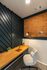 Elegant home office nook with chic diagonal wall design, cozy chair, warm lighting, and a streamlined wooden desk.