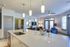 Modern open-concept living room and kitchen with elegant decor, featuring a stylish island, cozy seating area, and large windows for natural light.