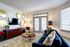 Chic living room with a plush rug, stylish navy sofa, and elegant gold decor accents, bathed in natural light from large windows.